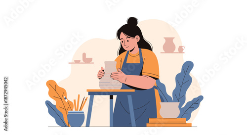 A young woman wearing an apron is concentrating as she shapes a piece of clay on a pottery wheel in her art studio.