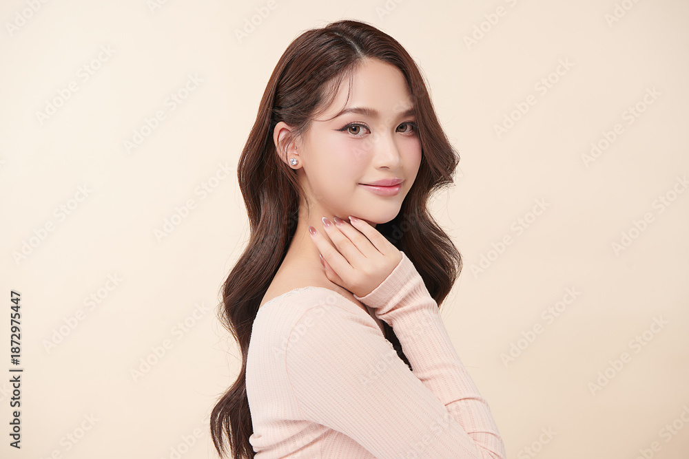 Fototapeta premium A beautiful young Asian woman with clean, fresh skin against a beige background. Skincare, facial treatment, cosmetology, beauty, and spa. An elegant portrait of an Asian woman.