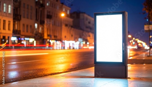 Bright blank digital billboard display illuminating a wet city street at night, perfect for advertising and marketing campaigns in an urban environment
