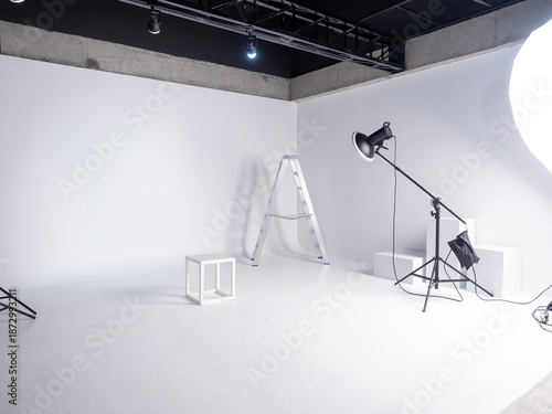 Empty White Photography Studio with Lighting Equipment, Ladder, and Minimal Props