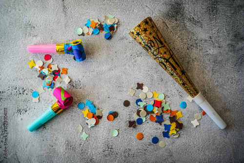 Party whistles, horns and confetti on neutral background