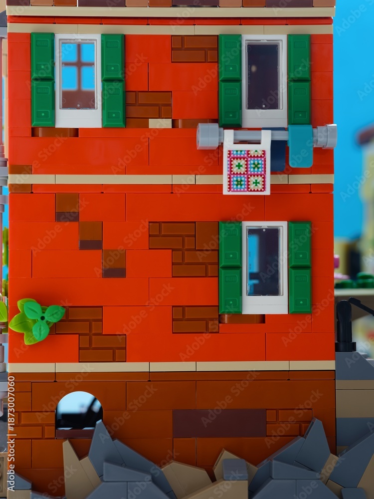 Fototapeta premium Tambov, Russian Federation - January 05, 2026 A close-up shot of a red two-story Lego building, featuring green shutters, white-framed windows. LEGO Ideas Italian Riviera set.