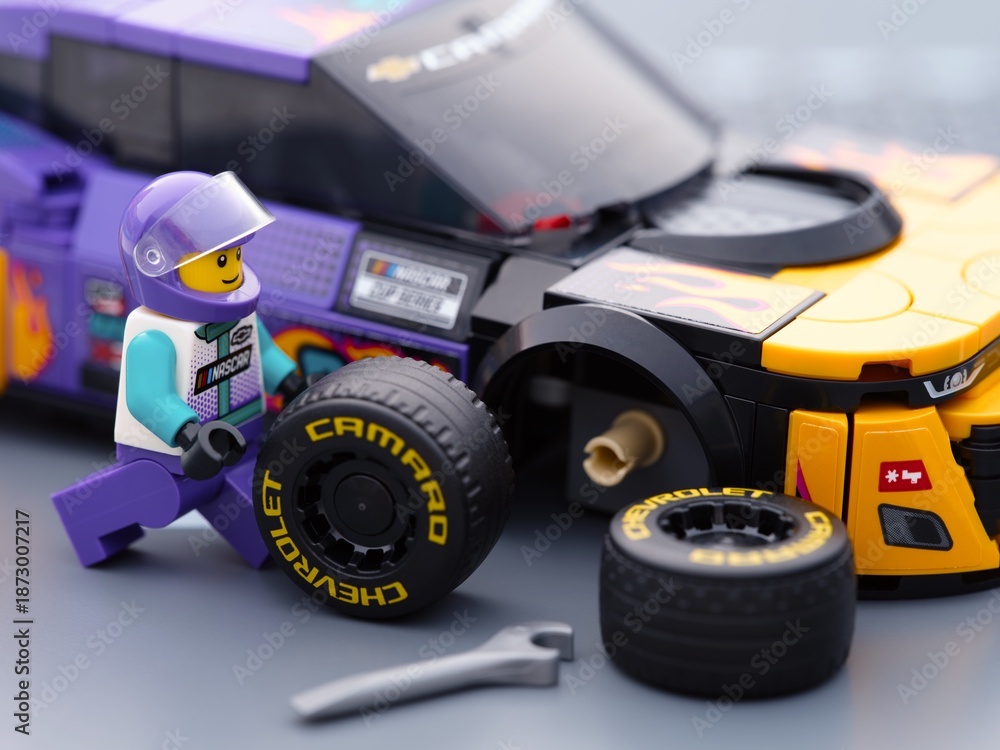 Naklejka premium Tambov, Russian Federation - January 02, 2026 Lego driver minifigure changing wheel of the Lego NASCAR Next Gen Chevrolet Camaro ZL car. LEGO Speed Champions.