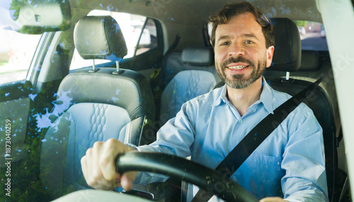 Smiling man driving car, wearing seatbelt, looking at camera. Commuting daily, safe journey, happy adult motorist