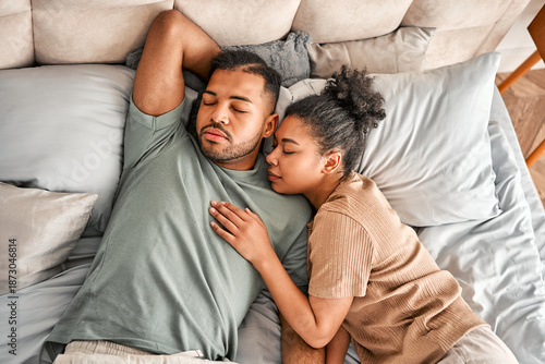 A loving married couple in pajamas is sleeping together, tightly embraced on comfortable pillows and a cozy bed. Deep sleep and comfort.