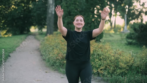 A middle-aged woman warms up before a morning workout in the park.