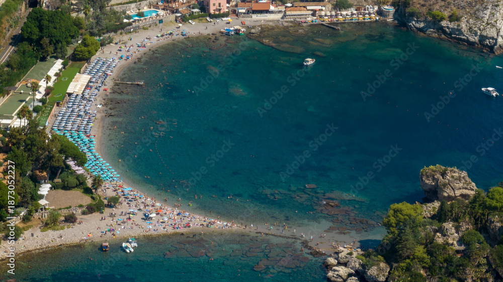 Fototapeta premium Aerial view of the beach of Isola Bella, in Sicily, Italy. It is a small bay with crystal-clear turquoise waters overlooking the Ionian Sea, near Taormina. It is a popular tourist destination.
