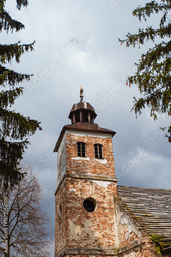 Old brick church with a bell tower surrounded by trees on a cloudy day. Ukraine
