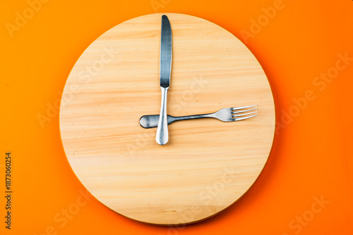 The concept of intermittent fasting and skipping meals. Wooden round tray with cutlery in the form of clock hands