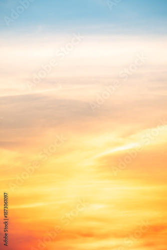 Sunset or sunrise sky with a vibrant gradient of orange, gold, and soft blue. Clear atmosphere with wispy clouds. Peaceful, natural light background. hope, freedom, new day Concepts, Vertical
