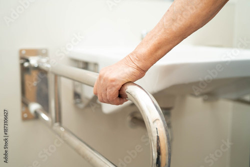 Fotografi Asian elderly woman use safety handrail in bathroom.