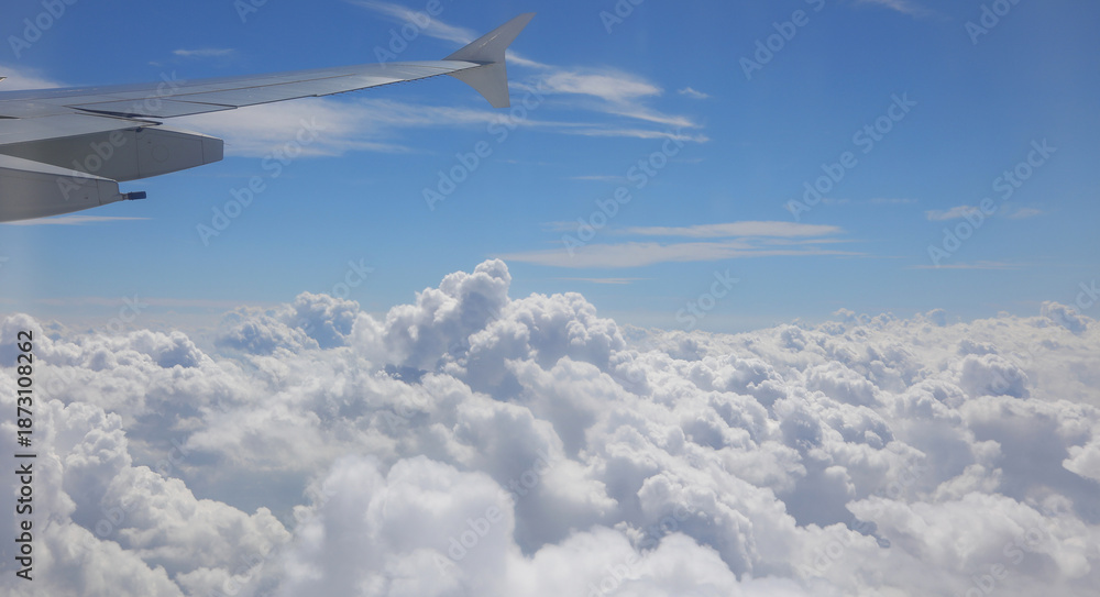 Fototapeta premium white clouds at 40000 feet altitude from the airplane seeing a piece of the wing