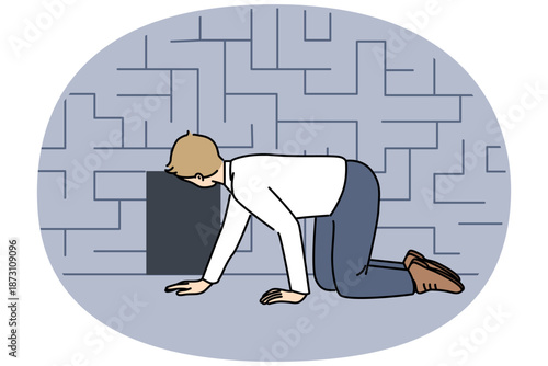 Man searching exit from labyrinth, crawling on floor near miniature door, as metaphor for difficult life situation. Guy is looking for way out of labyrinth, and needs hint or help.