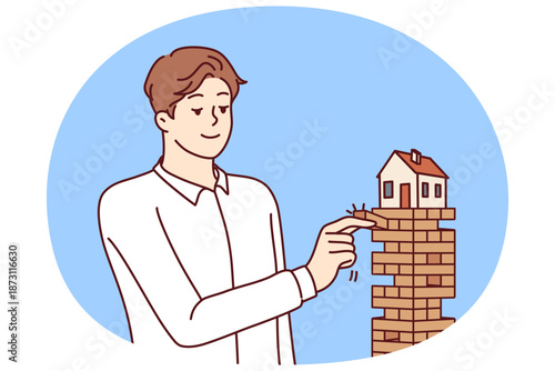 Man puts house in danger by pulling blocks from under building for concept of risky mortgage loan or pledge of real estate. House needs insurance and mortgage redemption from credit bank