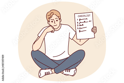 Man demonstrates checklist recommending time management and organizing own work. Smart smiling guy is sitting and holding checklist with tasks for day or step-by-step plan to achieve goal in hand