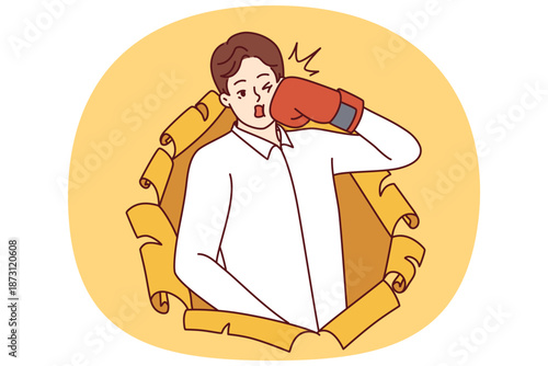 Man in boxing glove punches himself in face and peeking out of hole in torn paper. Young silly man boxer strikes, symbolizing actions that harm himself and cause problems in future.
