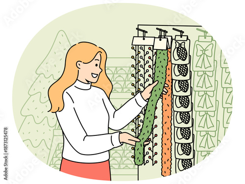 Woman chooses christmas decorations and garlands standing near store counter and new year tree. Happy girl getting ready for xmas celebration, buying souvenirs to create christmas atmosphere