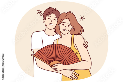 Couple suffers from sunstroke during summer heat and hugs feeling exhausted due to climate change. Man and woman with fan need refreshments and cool room after sunstroke caused by global warming.