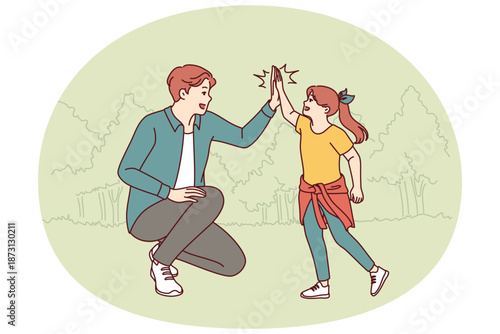 Dad gives hi-five to little daughter during walk together in park in hot summer weather. Cheerful teenager girl together with young dad is resting in nature enjoying active rest on sunday