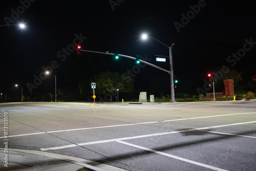 Empty intersection at night in Corona, California, featuring illuminated traffic lights, crosswalk markings, and wide urban roadway.