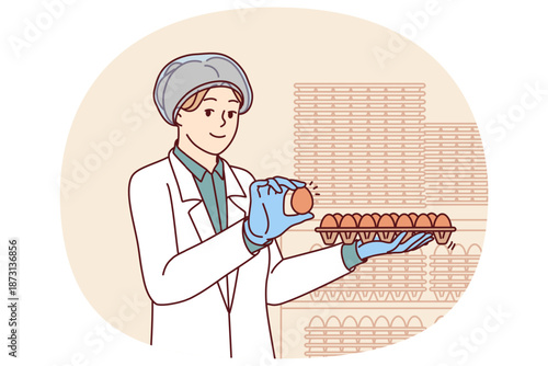 Woman factory worker holds chicken eggs while checking finished product for compliance with quality standards. Young girl factory technologist in white coat works in food industry.
