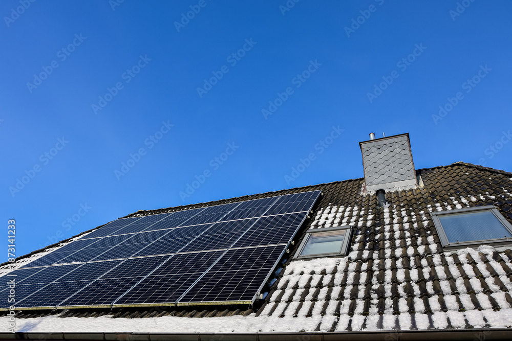 Fototapeta premium Solar panels generating clean energy on snowy roof