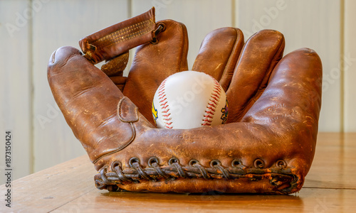 Fotografie Closeup of vintage 1940s baseball glove, with baseball, on a tabletop