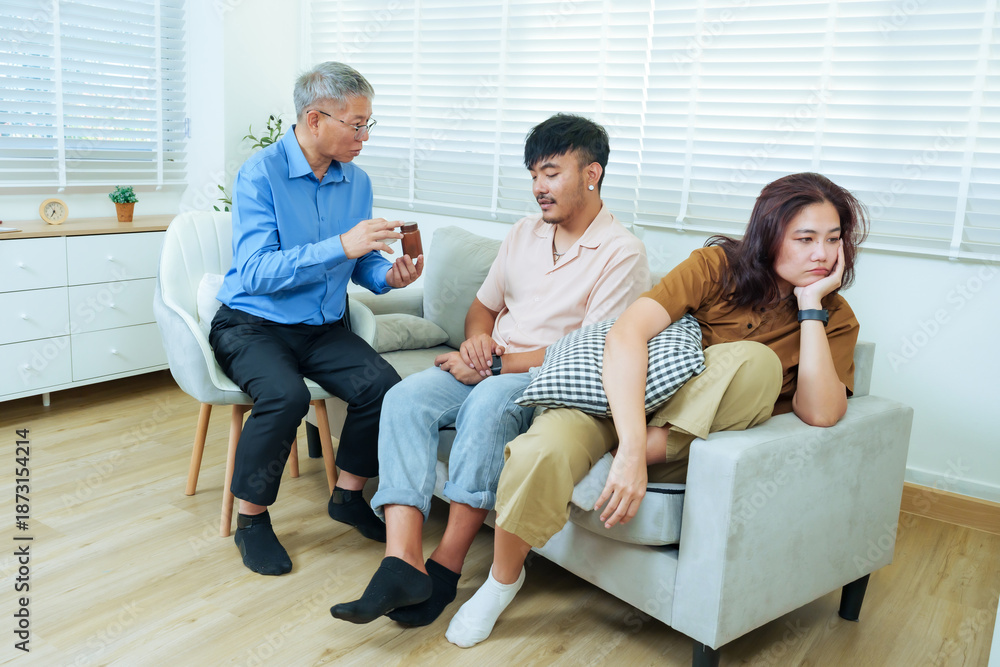 Fototapeta premium Senior asian psychiatrist talking with couple during therapy session, man explaining problems while woman looking discouraged, professional counseling for relationship issues, marriage conflict