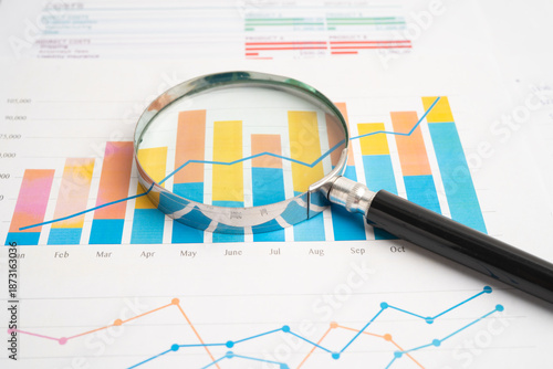 Magnifying glass on charts graphs paper.