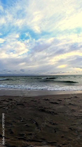 Calm Ocean Shoreline at Sunset with Soft Waves and Cloudy Sky