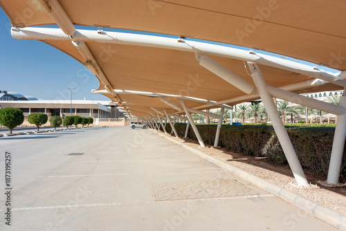 Sunny parking lot with beige shade sails and white support poles in modern complex