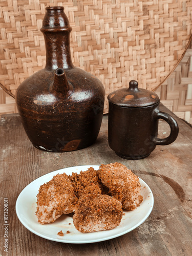 A plate of traditional Indonesian serundeng and ketan with bumbu on a rustic wooden table against a woven background.