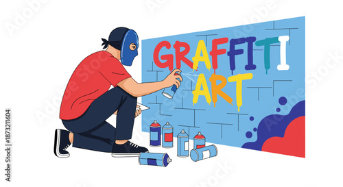 Masked street artist kneels on the ground while spray painting the words graffiti art in vibrant colors on a large blue wall.