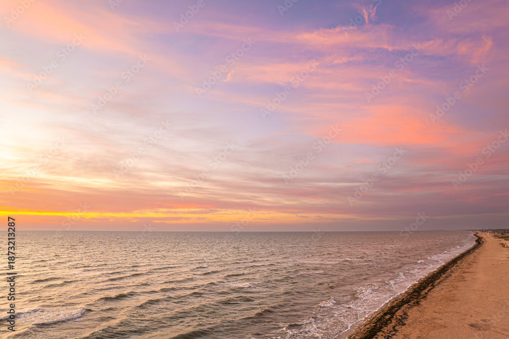 Obraz premium Sunset beach with gentle waves and colorful sky