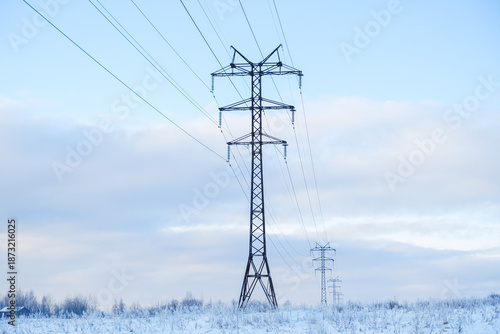 Russia, Saint Petersburg, 11.01.2026 Power lines and tall high voltage electricity pylons stretch across a snow-covered winter field against a light blue sky, concept of energy infrastructure.