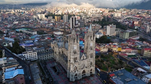 Aerial drone footage of the Basilica del Voto Nacional, one of the most iconic landmarks in Quito, Ecuador. Neo-Gothic architecture rising above the historic city, surrounded by urban landscape and An