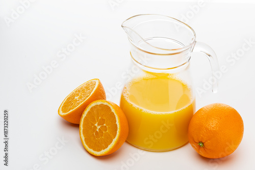 Photos Fresh orange juice and whole oranges on a white background with a pitcher