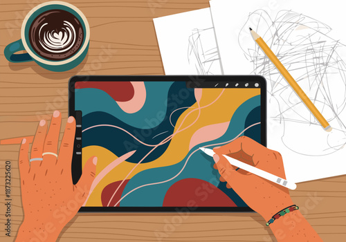 Artist creating abstract digital art on a tablet with a stylus, coffee cup on a wooden desk