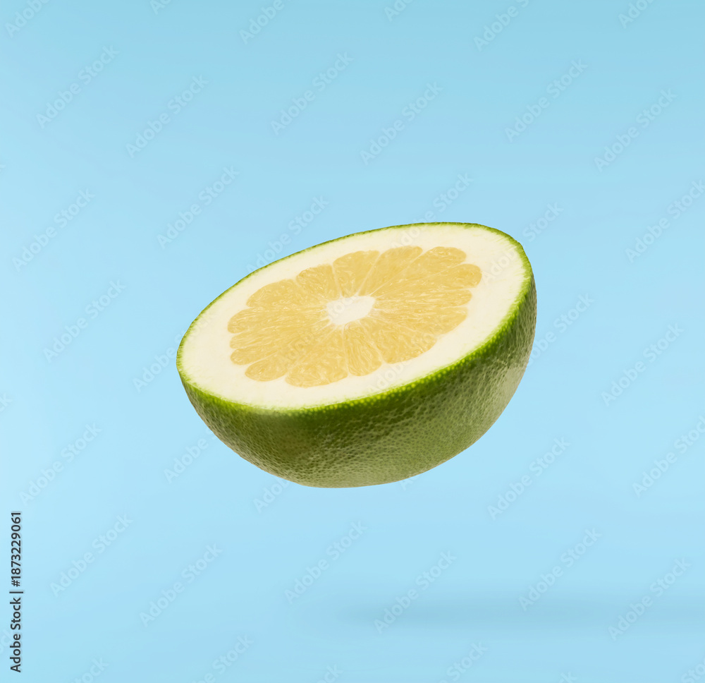 Fototapeta premium Fresh ripe green sweetie falling in the air isolated on blue background