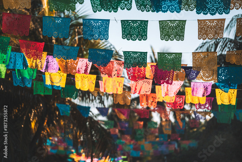 Close-up of colorful papel picado banners hanging among palm trees in Tulum, Mexico.