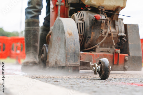 Canvas Print Construction worker cutting asphalt road surface with petrol power road saw and
