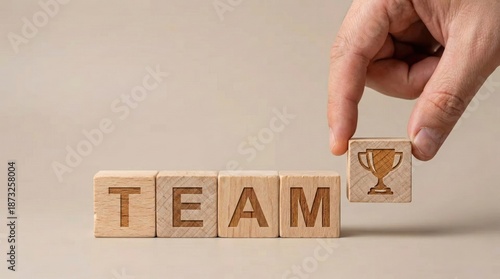 Teamwork and Success: A hand places a trophy block onto the word 'TEAM', symbolizing the culmination of collaborative effort and the achievement of shared goals.