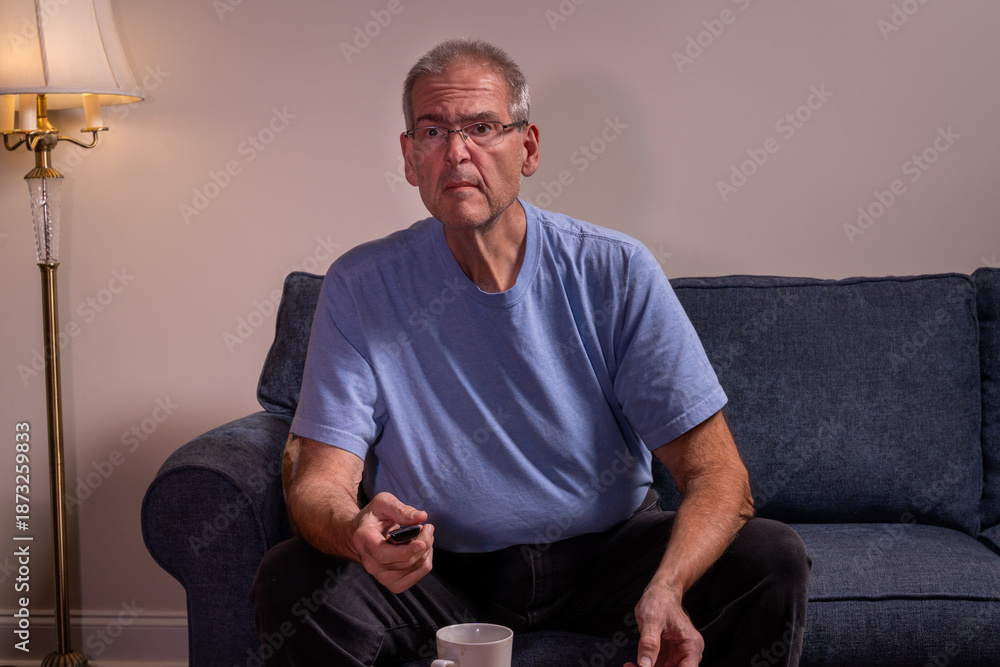 Fototapeta premium Older man watching TV with intent in a dimly lit room