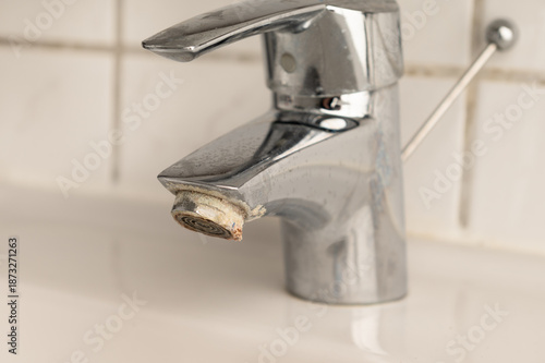 Εκτύπωση καμβά Close-up of a worn bathroom faucet with visible limescale and corrosion on the aerator, illustrating problems caused by hard water, mineral buildup, and lack of plumbing maintenance