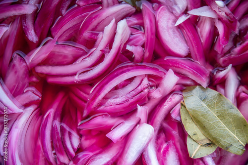 Slika na platnu Pickled red onion sliced into thin strips with bay leaf, vivid color and visible