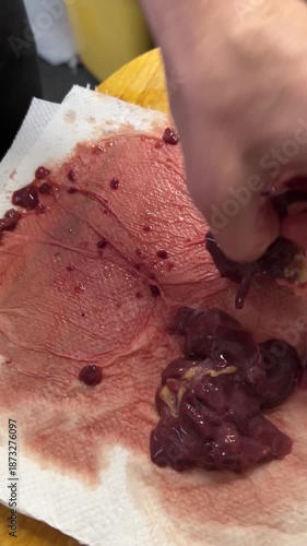 Vertical close-up video of raw liver placed on a white napkin on a wooden cutting board and gently tenderized with a kitchen mallet. Home cooking process, food preparation, rustic kitchen concept.