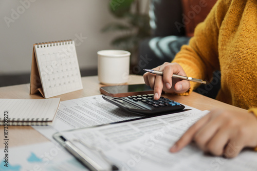 The concept of tax return preparation and financial management. Businessman calculates taxes using calculator and laptop. finance, Income tax, tax documents, and savings