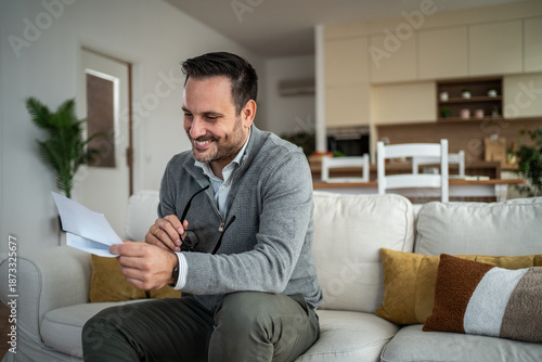 Photos Happy man smiling reading good news letter at home