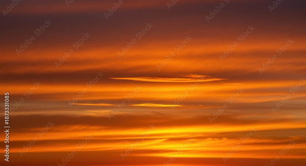 Obraz premium Vibrant orange sunset illuminating wispy clouds high above the horizon, creating a warm, dramatic atmospheric display ,outdoor ,peaceful ,freedom