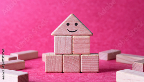Happy home positive living concept wooden toy house block smile, playful minimalist design on pink background, childlike joy and comfort